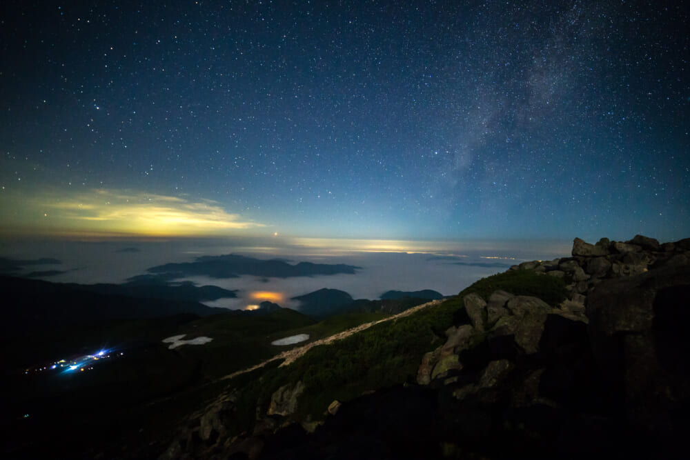御前峰から眼下の室堂の灯りと雲海、星空を撮影した写真